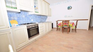 Une cuisine avec des meubles blancs, une cuisinière à gaz et un dosseret carrelé.