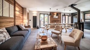 A modern living room with a sofa, chairs, a wooden coffee table, and a dining area with a table and chairs.