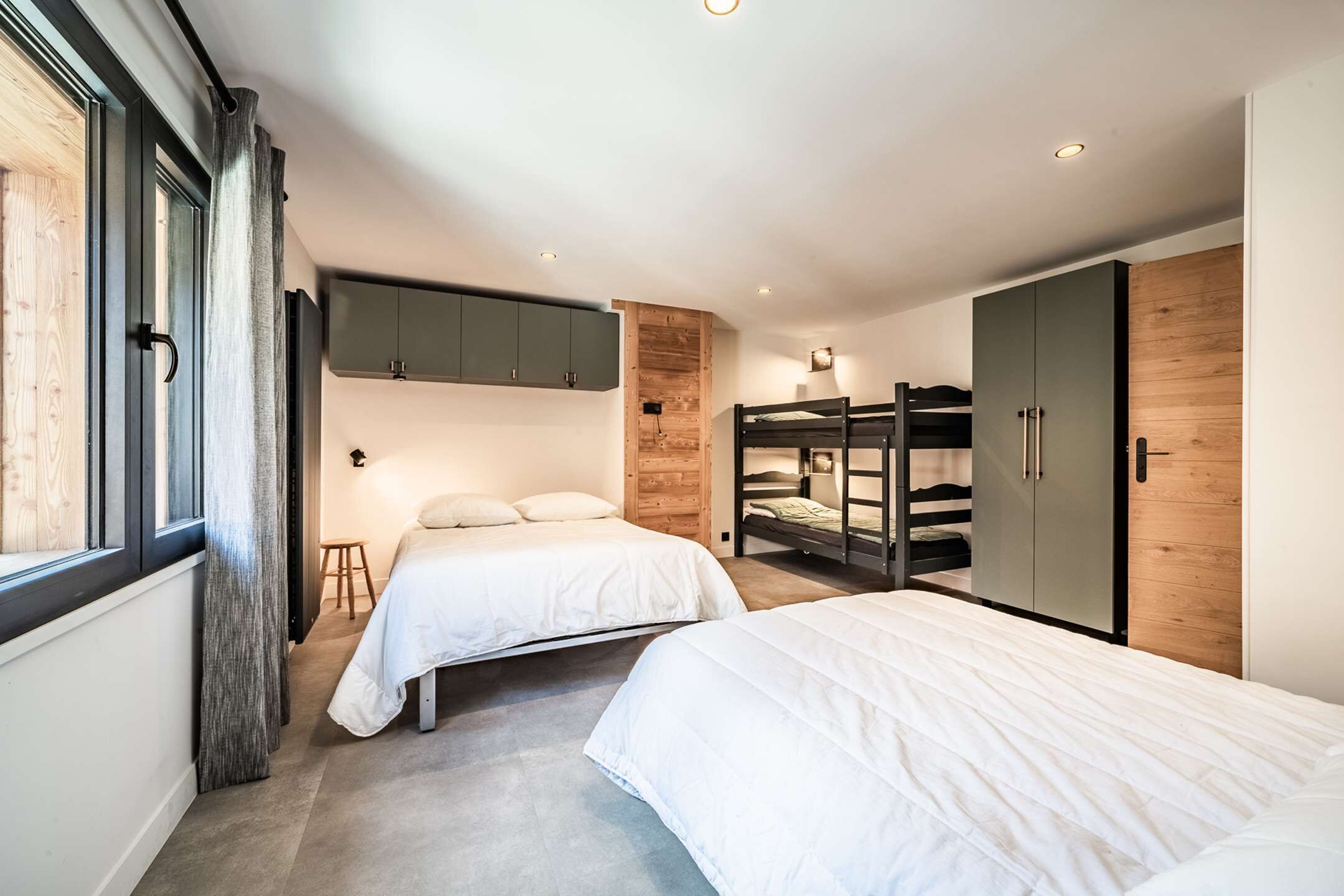 A bedroom with two beds, a wooden wardrobe, and a bunk bed.