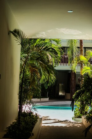 A pool area with palm trees and a balcony.