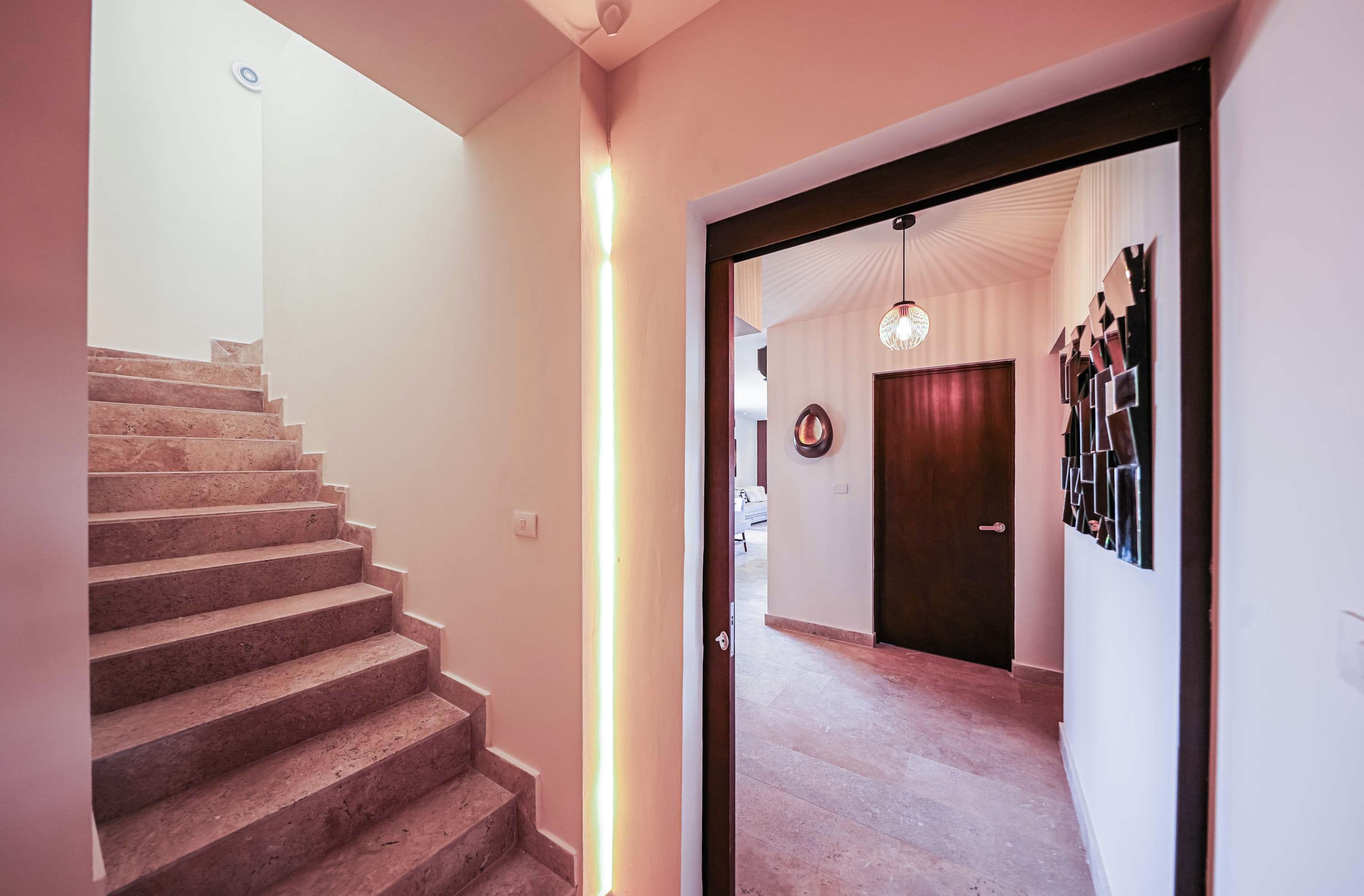 A staircase leading to a landing with a door and a wall-mounted light fixture.