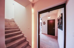 A staircase leading to a landing with a door and a wall-mounted light fixture.