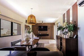 Una sala de estar moderna con comedor, televisor de pantalla plana y ventilador de techo.