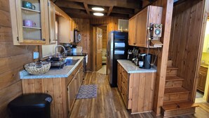 Une cuisine de style rustique, avec des murs en bois, un îlot central, des armoires en bois et une horloge intégrée.