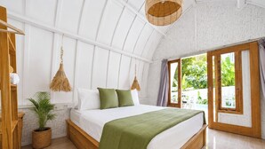 Een ruime slaapkamer met een groot bed, een houten hoofdbord, een hanglamp en uitzicht op groen.