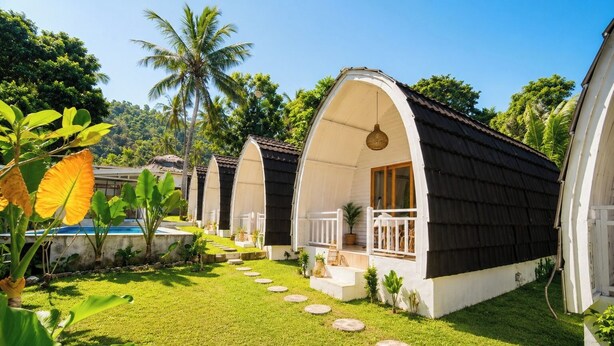 Een rij bungalows met gebogen daken, een verzorgd gazon en een heldere lucht.