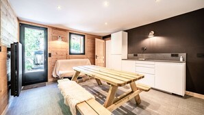 Una cocina compacta con una mesa de madera y un banco, un refrigerador y un lavamanos.