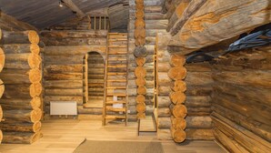 A log cabin interior with a central wooden ladder, a small table, and a mat on the floor. - Lumikenttien kutsu by Interhome (Kuusamo)