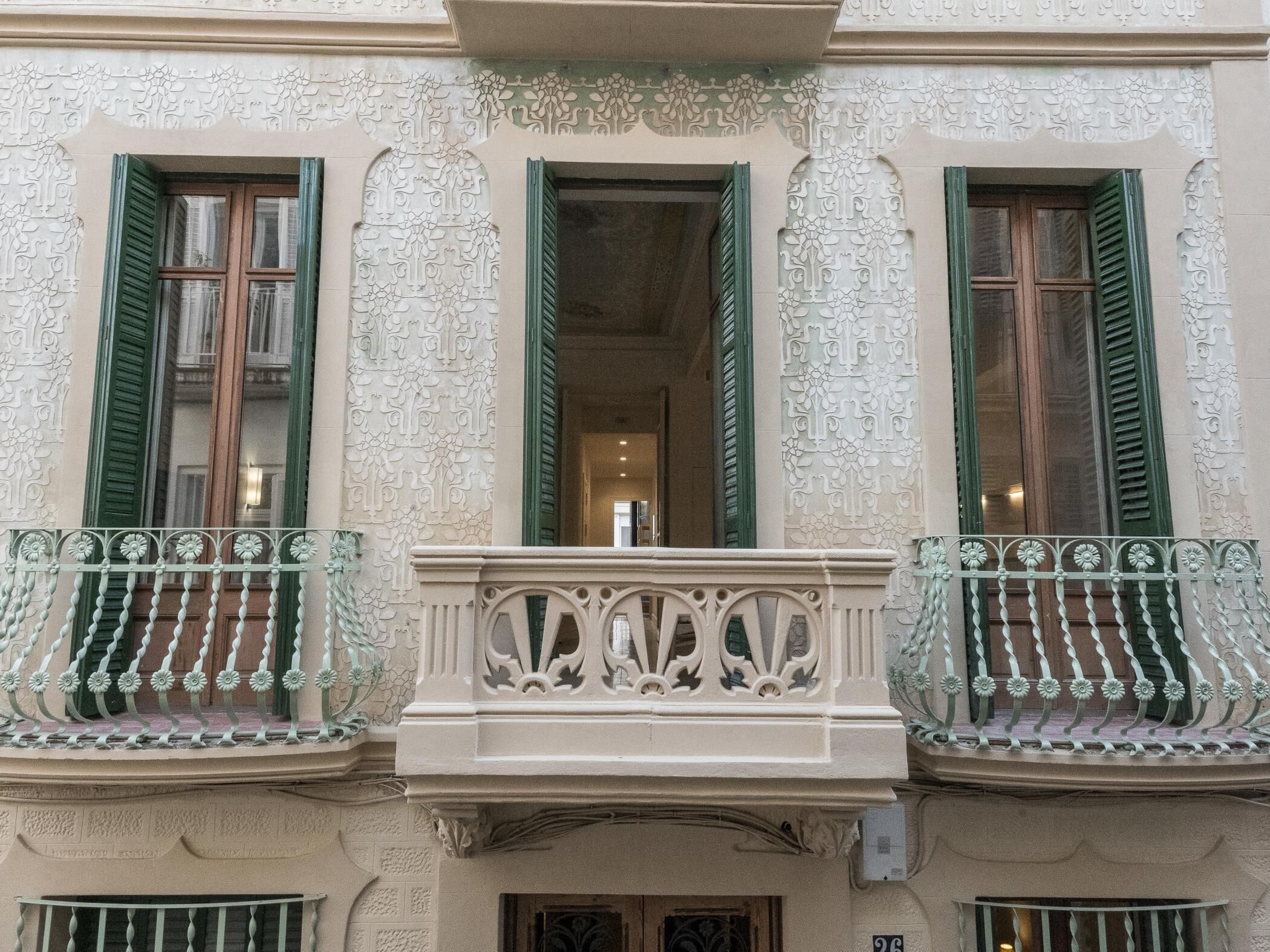 A building facade with ornate architectural details, including decorative moldings and a balcony with a wrought iron railing.