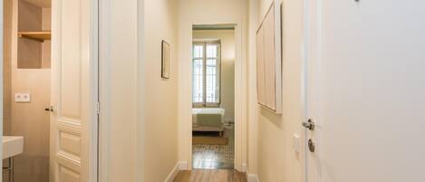 A hallway with wooden flooring, white walls, and doors leading to different rooms.