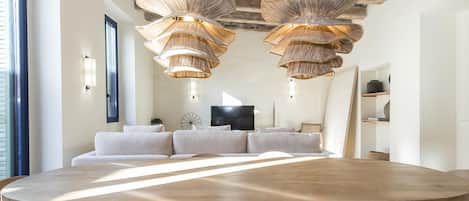 A spacious dining area with a large wooden table and woven pendant lights.