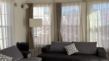 Una sala de estar moderna con un sofá gris oscuro, una mesa redonda de centro y una mesita de noche de madera.