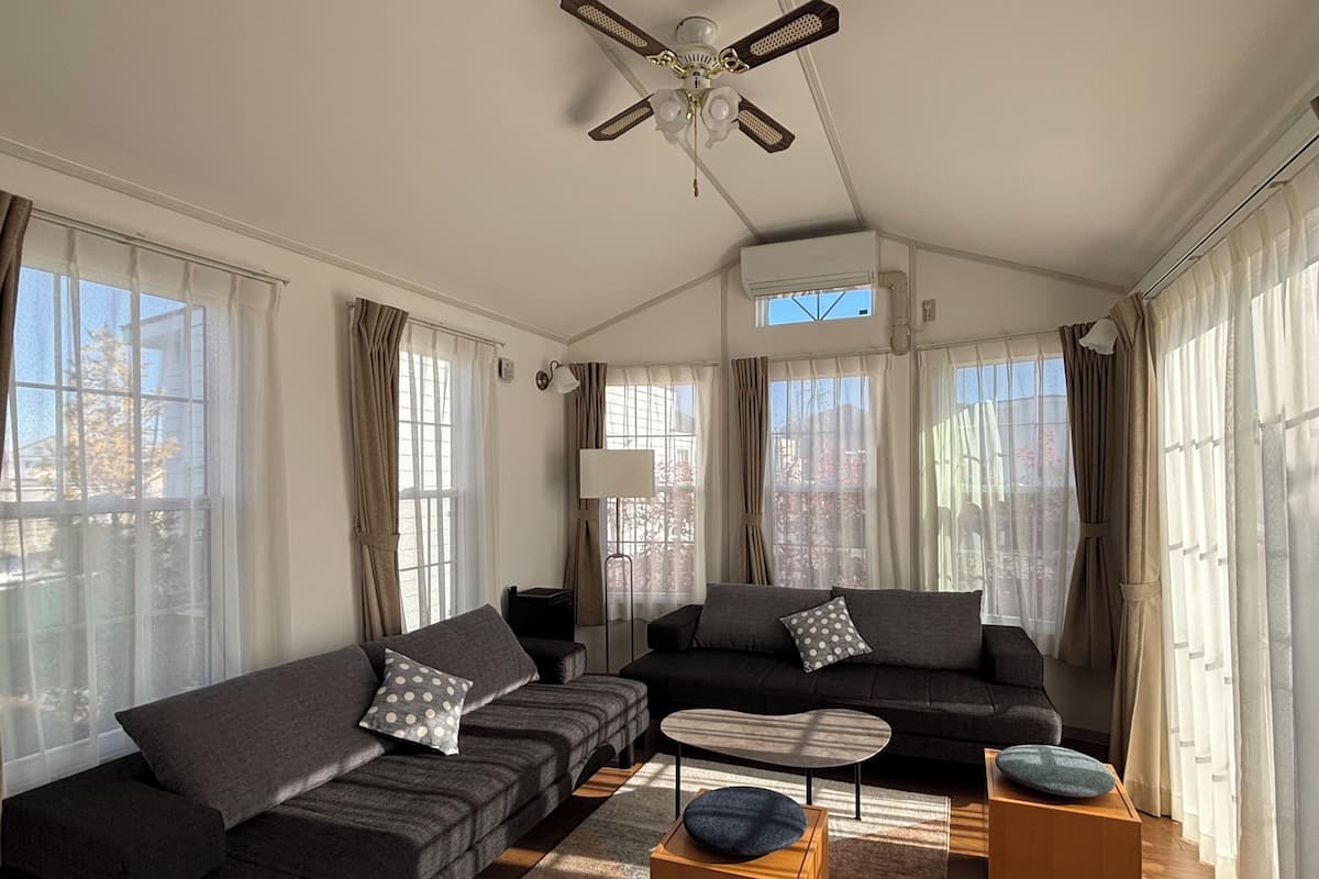 Un salon moderne avec deux canapés, une table basse et un ventilateur de plafond.