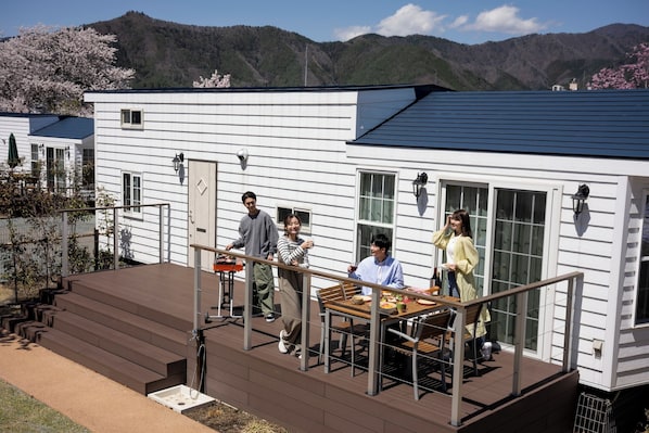 Ein modernes Haus mit einer Terrasse, einem Essbereich und Blick auf die Berge.