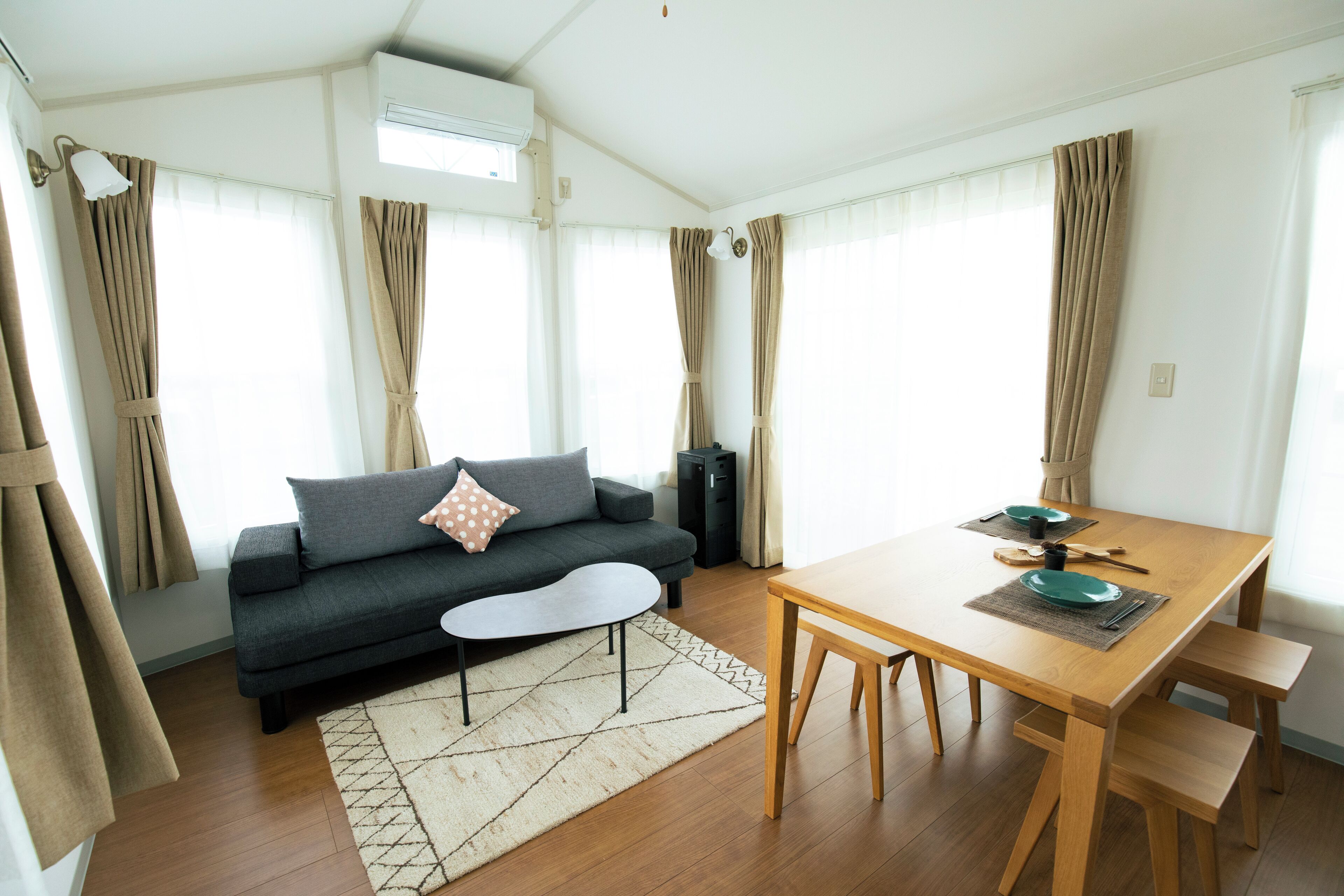 A modern living room with a sofa, coffee table, dining table, and chairs.