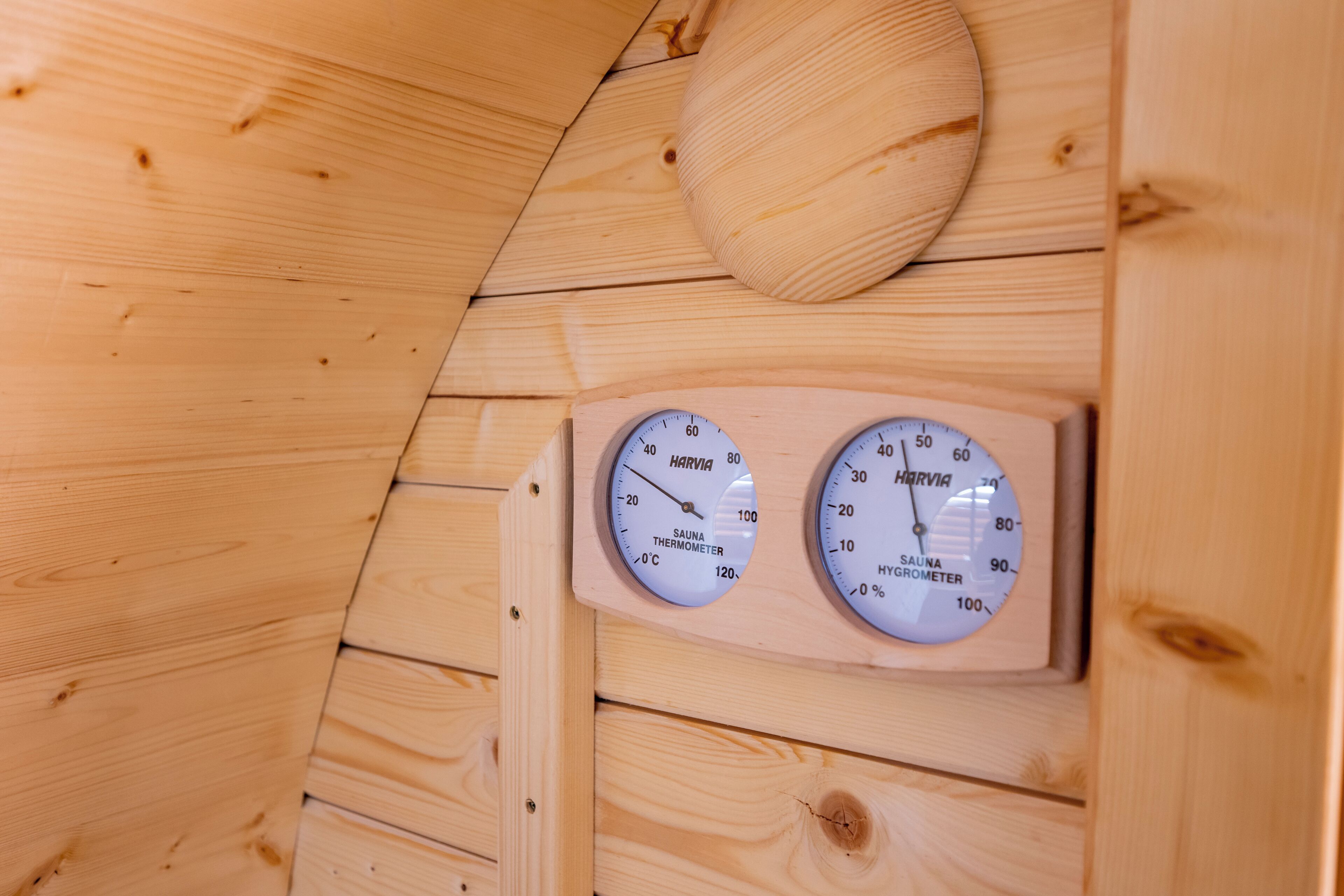 A wooden sauna with two thermometers, one for temperature and one for humidity.