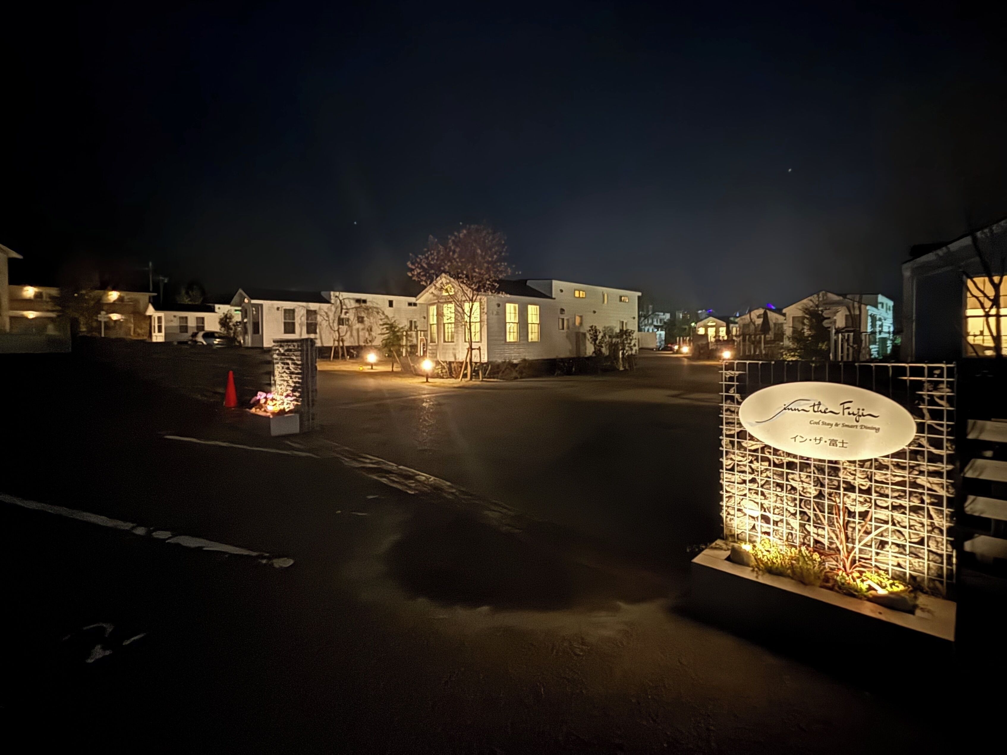A nighttime view of a residential area with houses and a gated entrance.