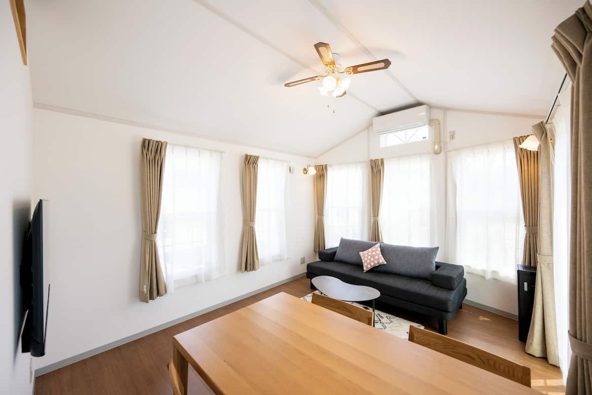 Un salon moderne avec un canapé, une table en bois et un ventilateur de plafond.