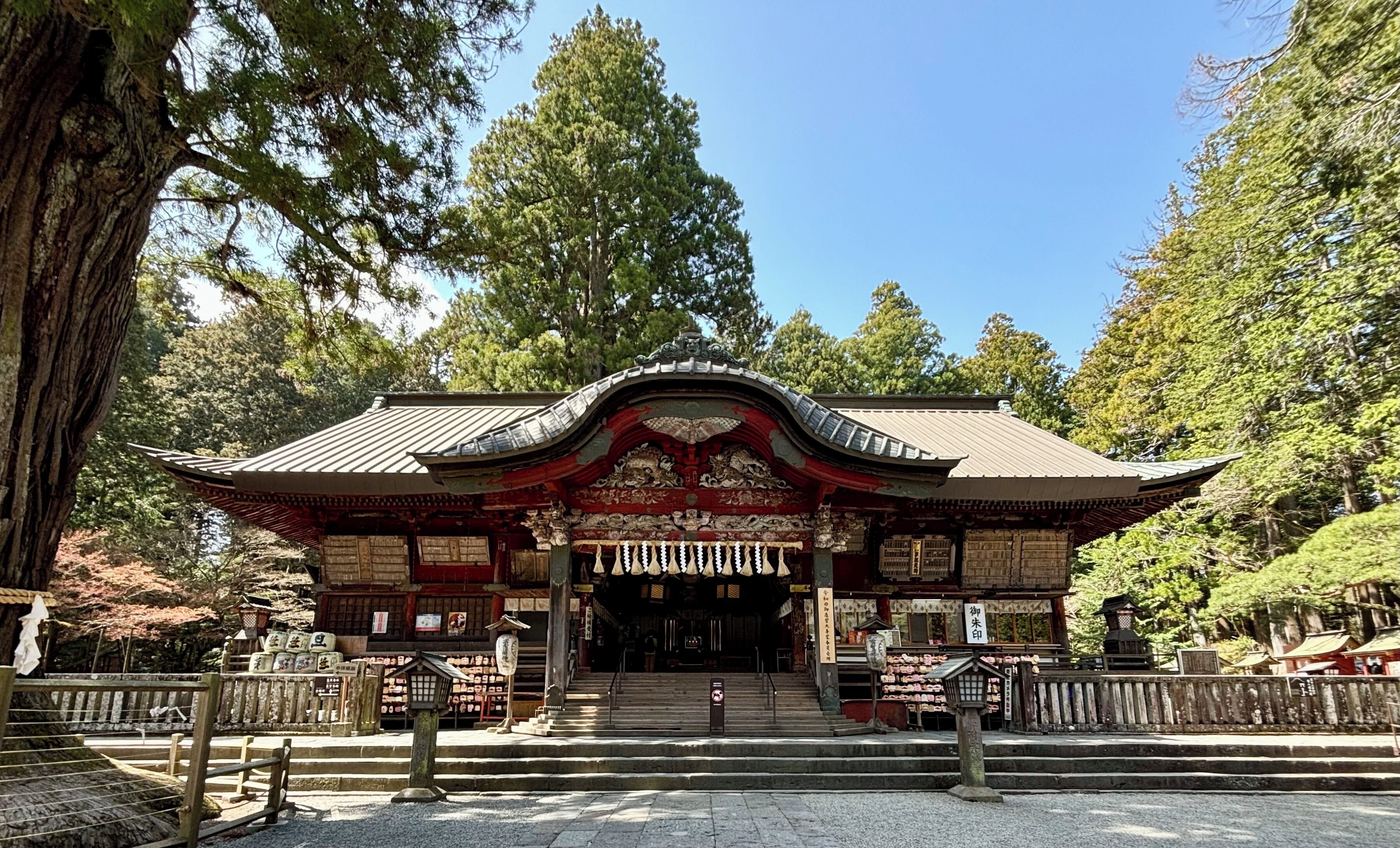 A traditional Japanese temple entrance with a curved roof, wooden structure, and steps leading up to it.