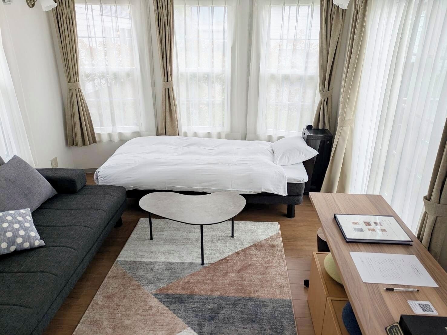 Una habitación de hotel moderna con una cama, un sofá, una mesita y un escritorio con una silla.