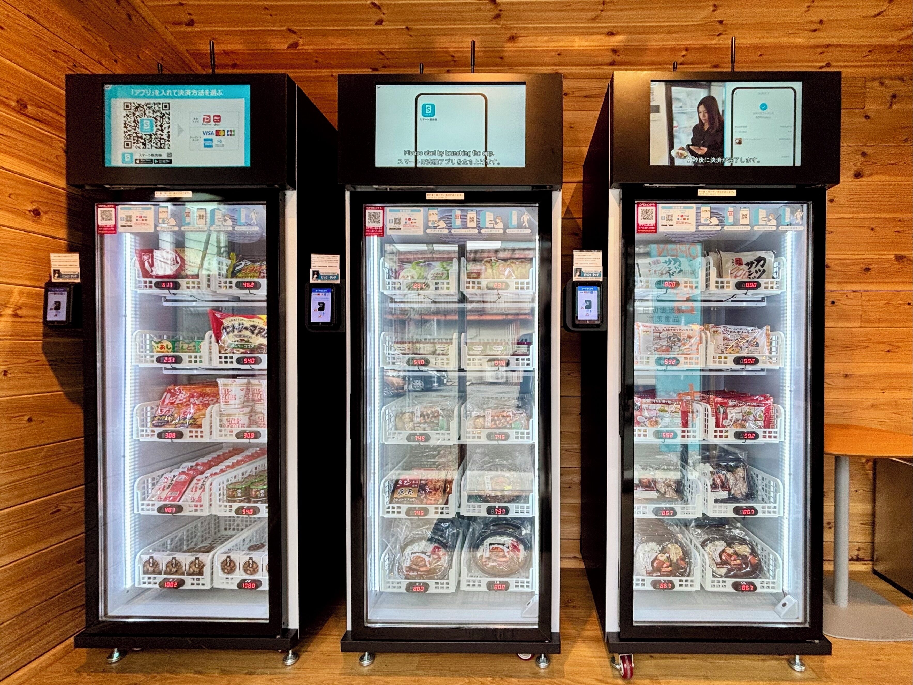 Three refrigerated display cases with various packaged food items, each with a digital price tag and a QR code.