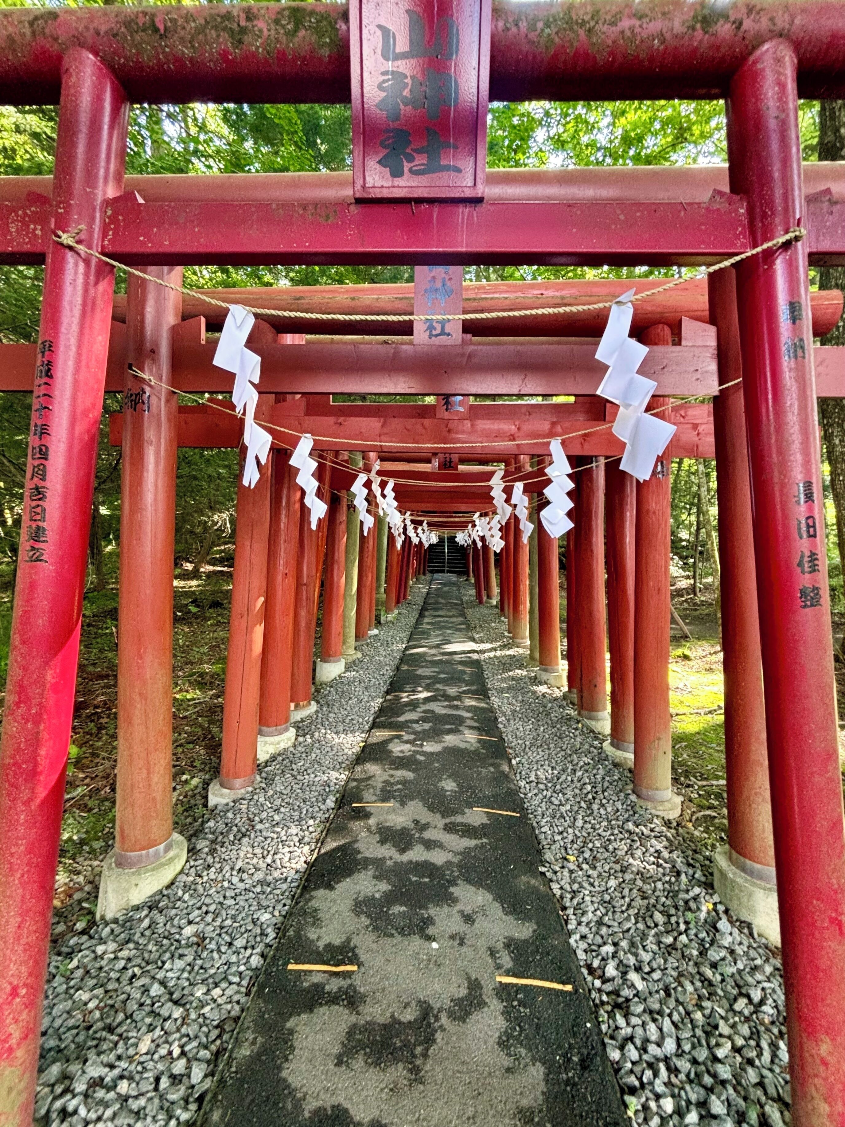 A pathway with red pillars and white paper decorations.