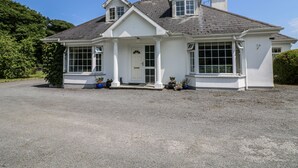 Une maison à deux étages avec un porche à l’avant, de grandes fenêtres et une cheminée.