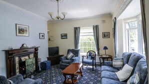 Un salon traditionnel avec une cheminée, une moquette à motifs et des meubles classiques.