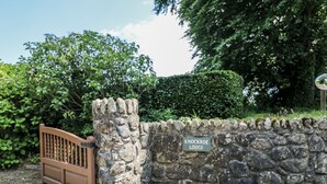 Un mur de pierre sur lequel est apposée une plaque indiquant « Knockroe Lodge ».