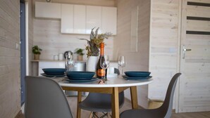 A dining area with a round table, four chairs, and a vase with a bottle. - Holiday Home With sea View in Ustronie Morskie (Ustronie Morskie)