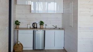 A compact kitchen with white cabinets, a stainless steel dishwasher, and a sink. There are two potted plants on the countertop. - Holiday Home With sea View in Ustronie Morskie (Ustronie Morskie)