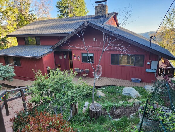 Una casa roja con techo inclinado, una chimenea y una terraza con muebles de exterior.