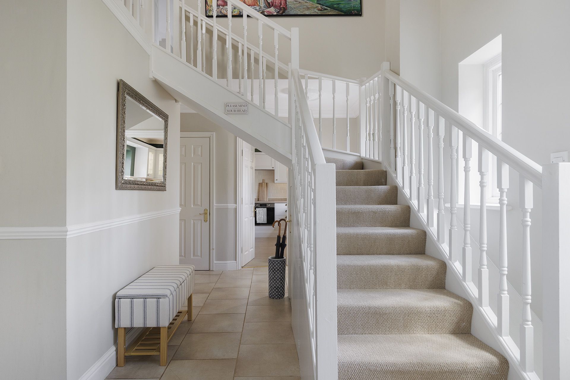 A staircase with white balusters and beige carpeted steps leading to a landing.