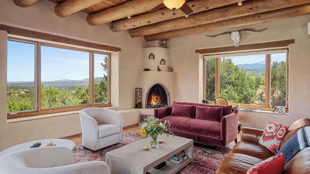 Un salón amplio con ventanas grandes, chimenea y ventilador de techo.