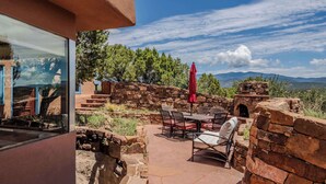 Un patio al aire libre con muros de piedra, una mesa con sillas y un paraguas rojo.