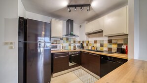 Una cocina moderna con refrigerador de acero inoxidable, horno empotrado, microondas y lavavajillas.