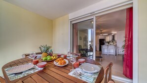 Comedor con una mesa redonda de madera dispuesta para una comida, incluyendo platos, cubiertos y un frutero.