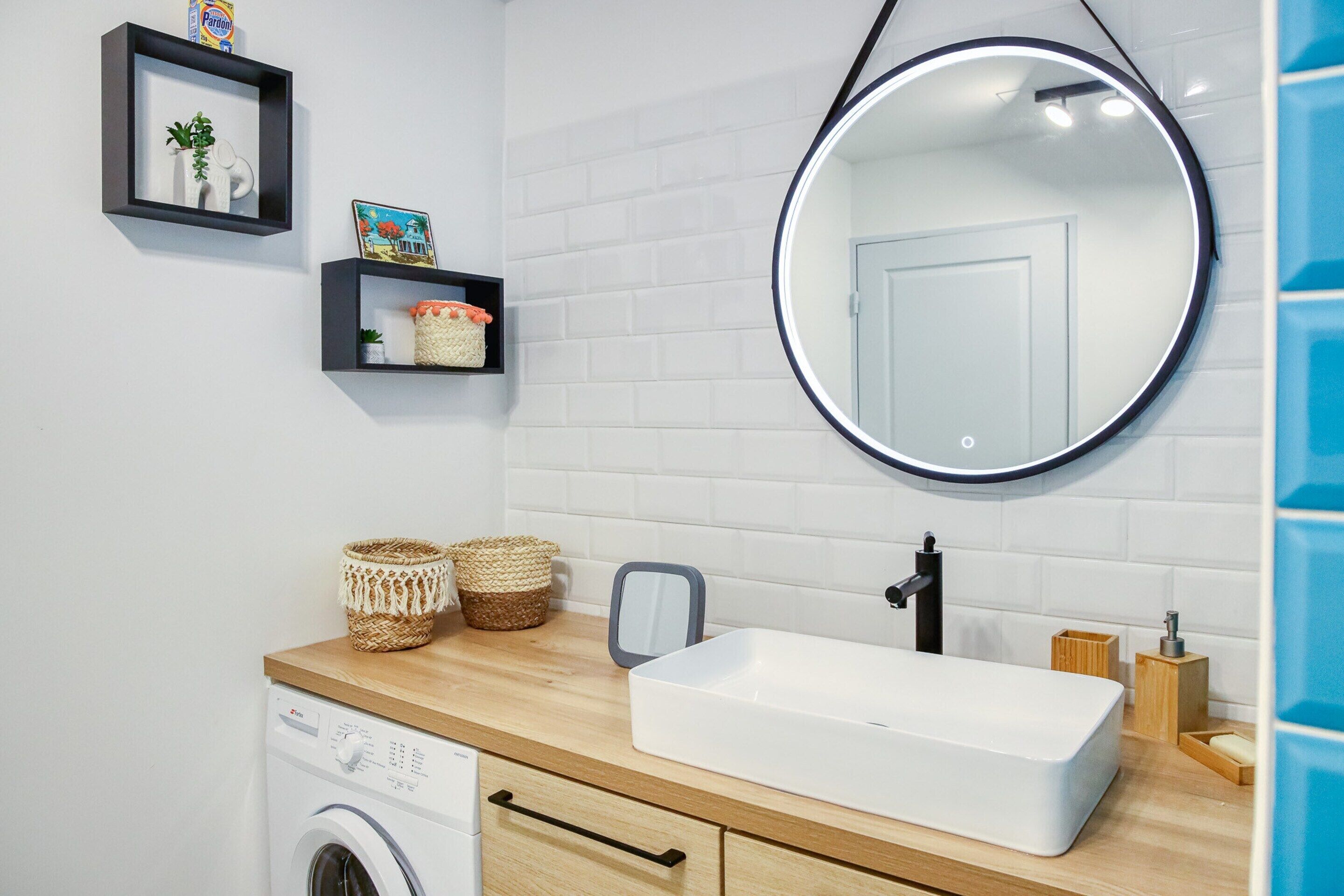 A modern bathroom with a washing machine, a sink with a mirror, and decorative baskets.