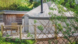 A yurt with a covered entrance, a wooden deck, and a seating area with chairs. - Willow Yurt - UKC6947 (Beaminster)