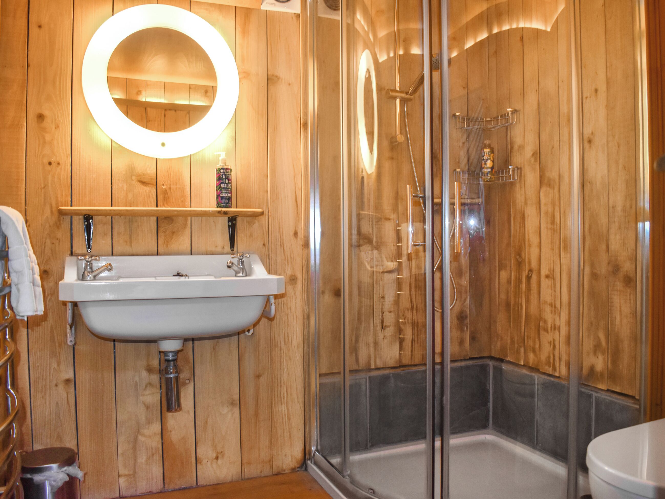 Une salle de bain en bois avec un lavabo, un miroir et une douche.