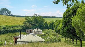 A yurt with a small adjacent building, surrounded by lush greenery and trees. - Bracken Yurt - UKC6941 (Beaminster)