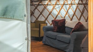 A cozy interior with a blue sofa, patterned rug, and a yellow chair. - Bracken Yurt - UKC6941 (Beaminster)