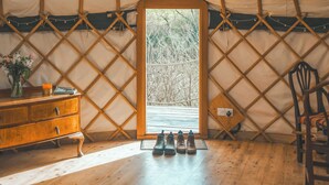 A cozy interior of a yurt with a wooden door, a dresser, and a chair. - Skylark Yurt - UKC6946 (Beaminster)