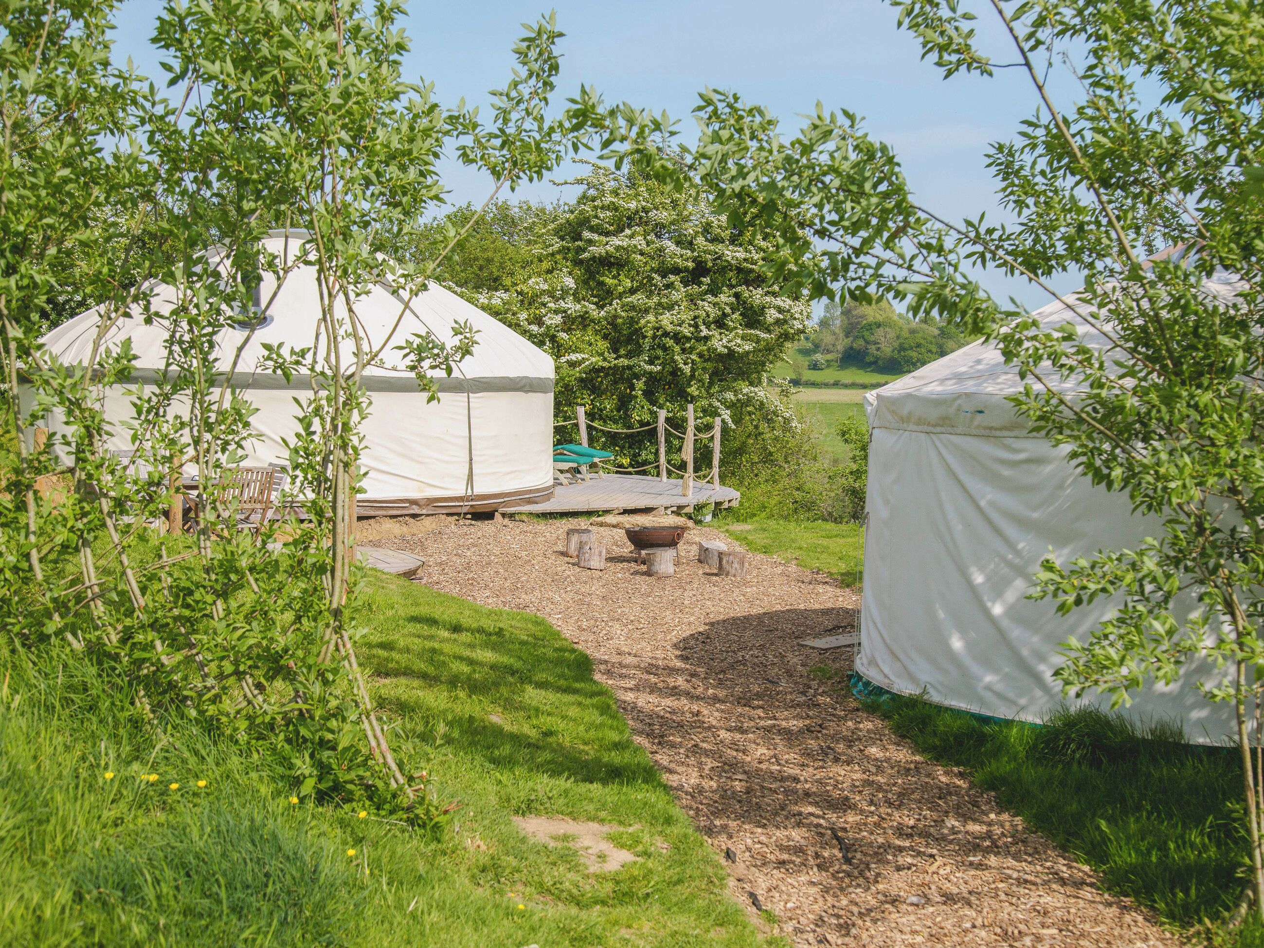 A yurt with a wooden deck and a fire pit in front.