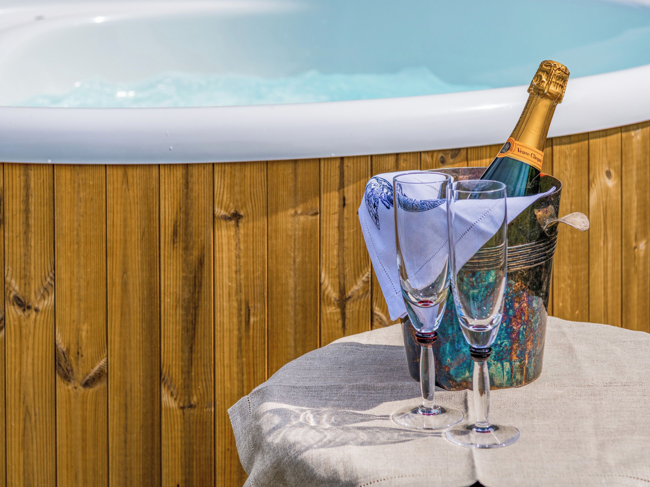 Eine Flasche Veuve Clicquot Champagner in einem Eimer mit zwei Gläsern auf einem Tisch.