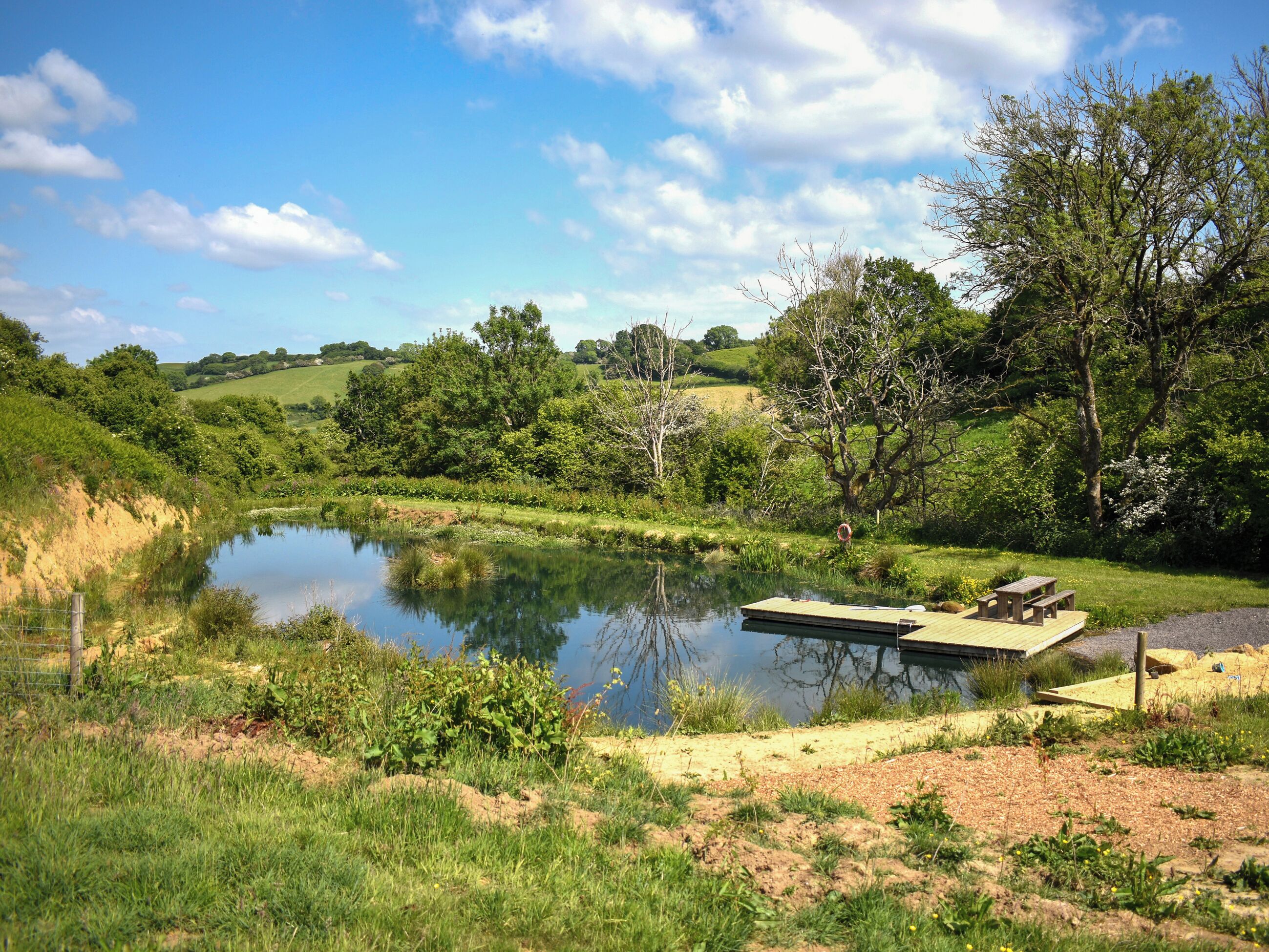 A serene lakeside setting with a wooden dock and picnic tables.