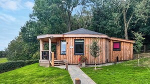Une cabane en bois avec une véranda, un petit jardin et un chemin de gravier menant à l’entrée.