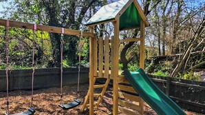 Una estructura de juego de madera con un tobogán y columpios.