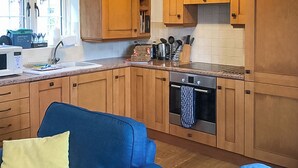 Een keuken met houten kastjes, een magnetron, een spoelbak en een fornuis.