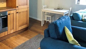 Een knus woongedeelte met houten kastjes, een eettafel en een blauwe bank.